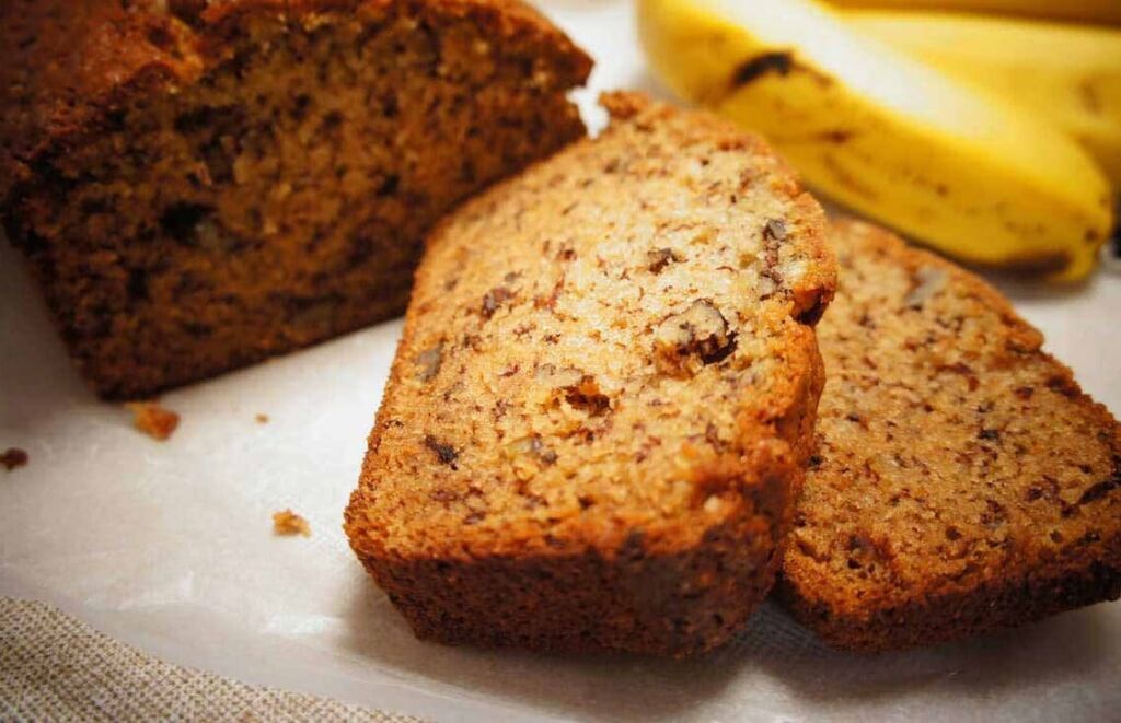 Mesa com bolo e pedaços de bolo cortados feito com farinha de banana verde.