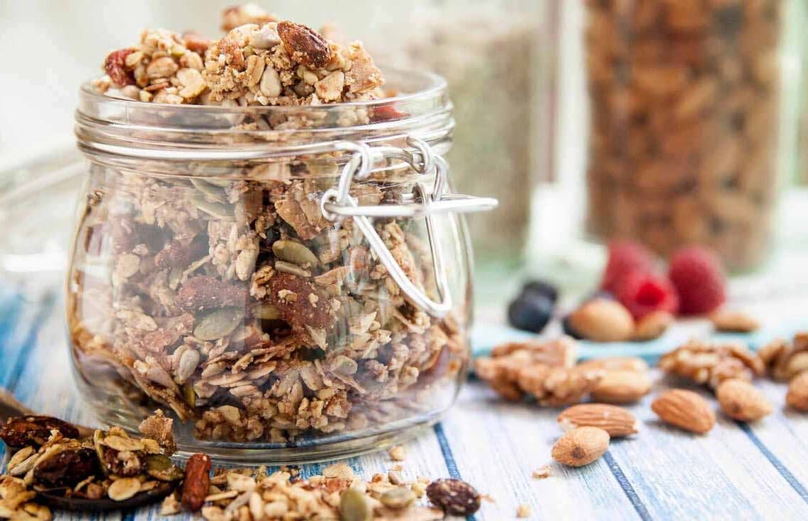 Mesa posta com um pote de vidro com a mistura de granolas.