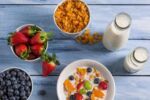 Mesa com várias opções saudáveis em tigelas para o café da manhã, como frutas, cereais e leite.