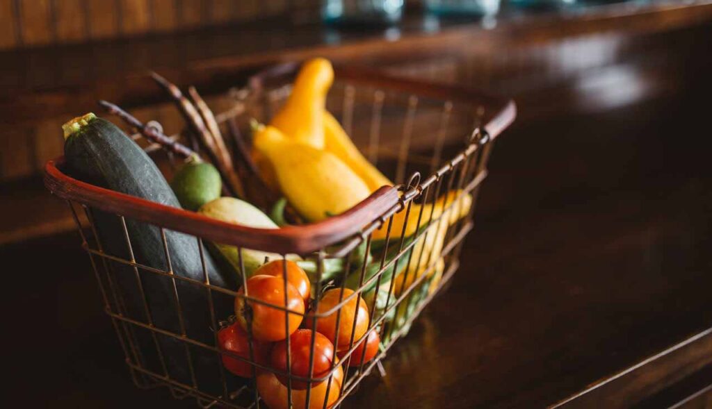 Mesa com cesta de supermercado com alimentos que representando a importância das fibras na alimentação