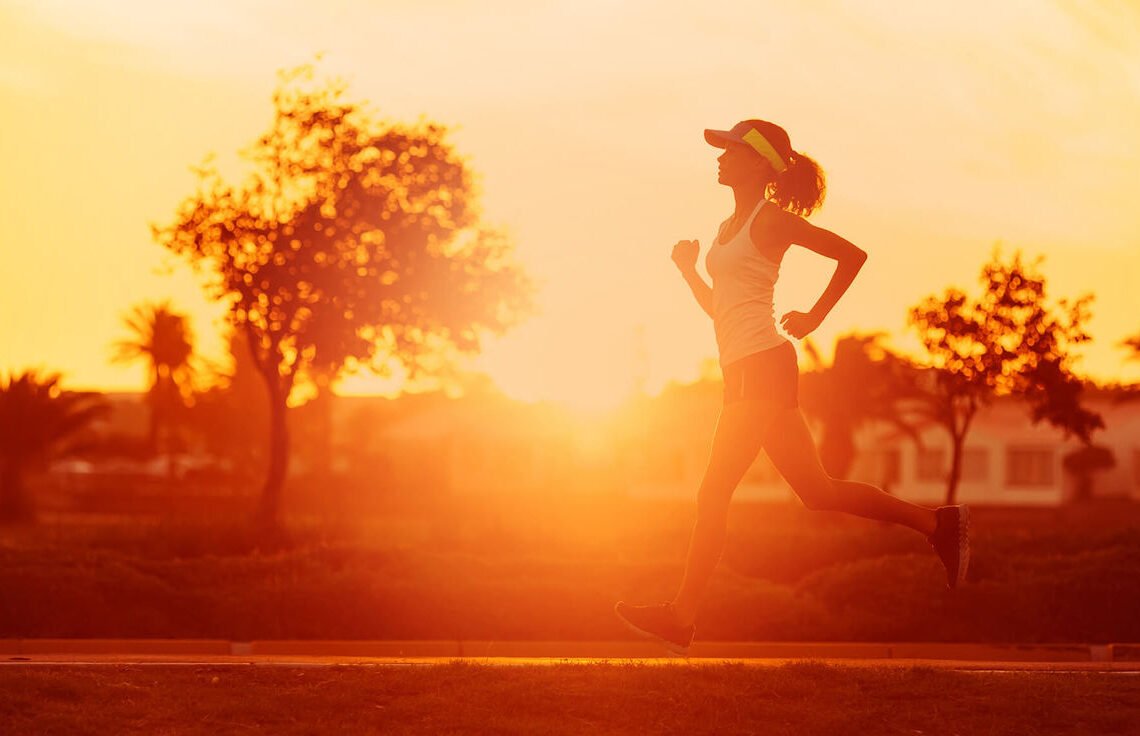 Mulher se exercitando enquanto corre ao ar livre no por do sol, após tomar seu termogenico.