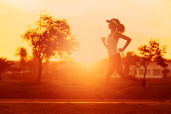 Mulher se exercitando enquanto corre ao ar livre no por do sol, após tomar seu termogenico.