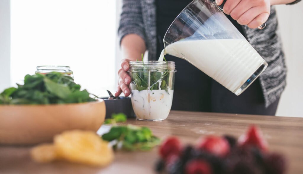 Homem em sua cozinha preparando um shake como substituto para sua refeição.