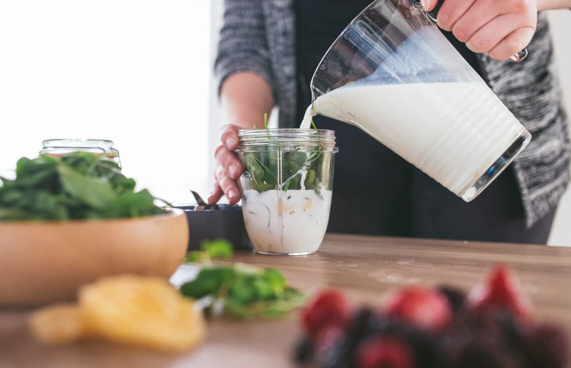 Homem em sua cozinha preparando um shake como substituto para sua refeição.