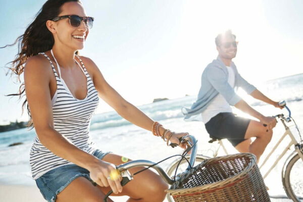 Um casal alegre se divertindo andando de bicicleta em uma praia.