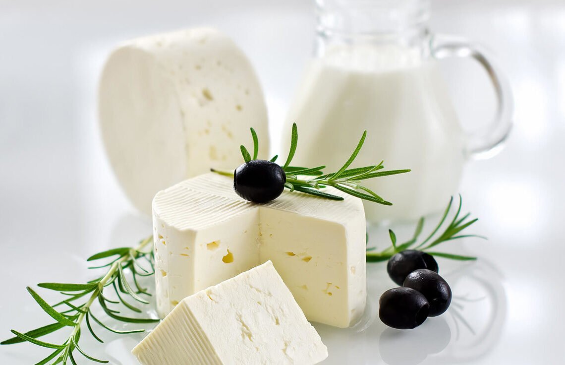 Mesa com laticínios para ganho de massa magra, como queijo branco e uma jarra com iogurte tradicional.
