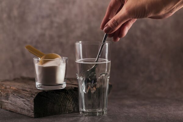 Mulher misturando um scoop de creatina em um copo com água
