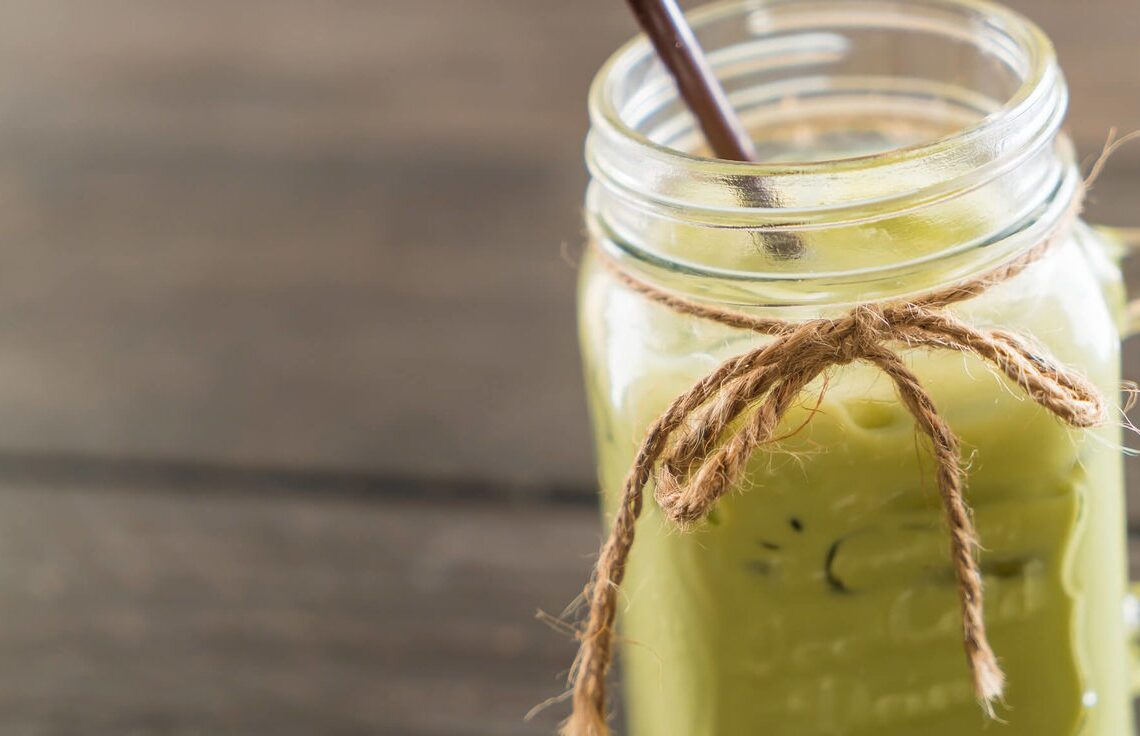 Uma caneca de vidro com chá verde dentro e um canudo, representando os alimentos termogênicos.