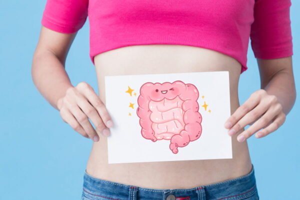Mulher segurando um papel com um desenho que representa a flora intestinal na frente de sua barriga.