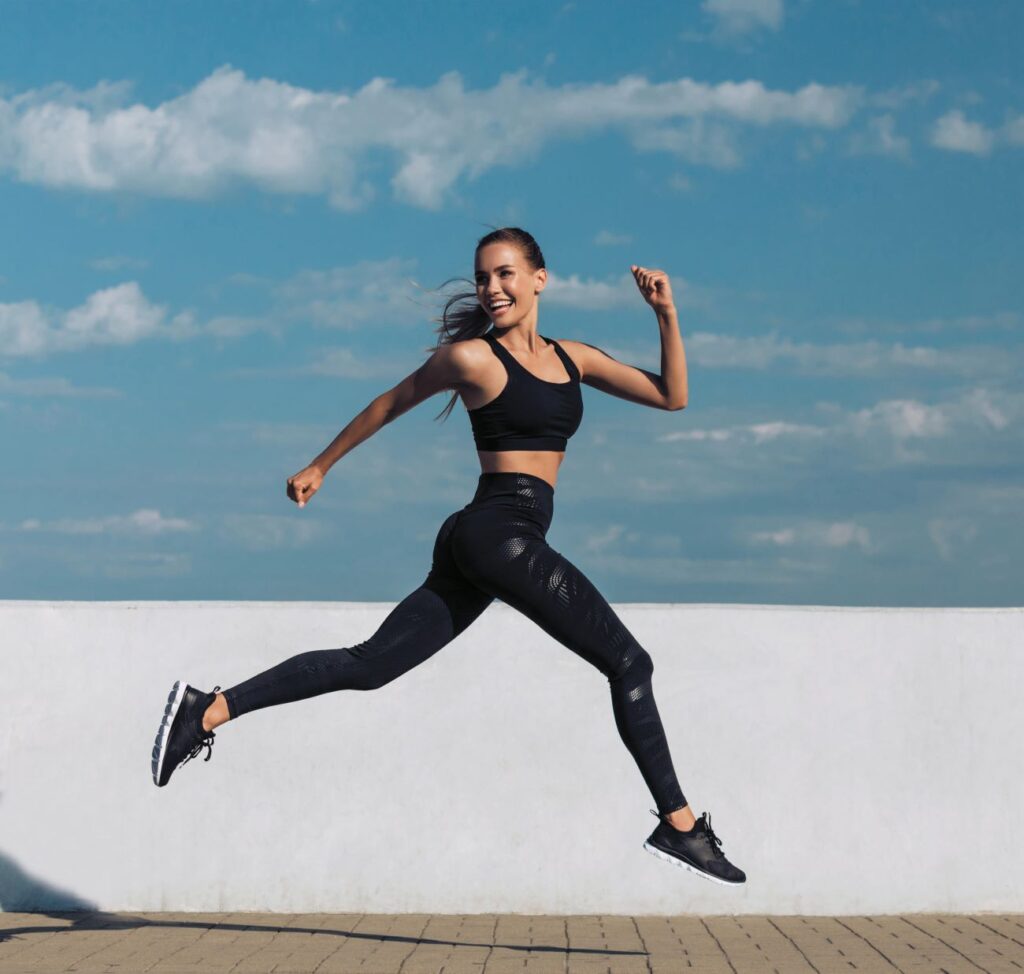 Mulher com roupa de ginástica correndo, sorrindo, olhando para trás