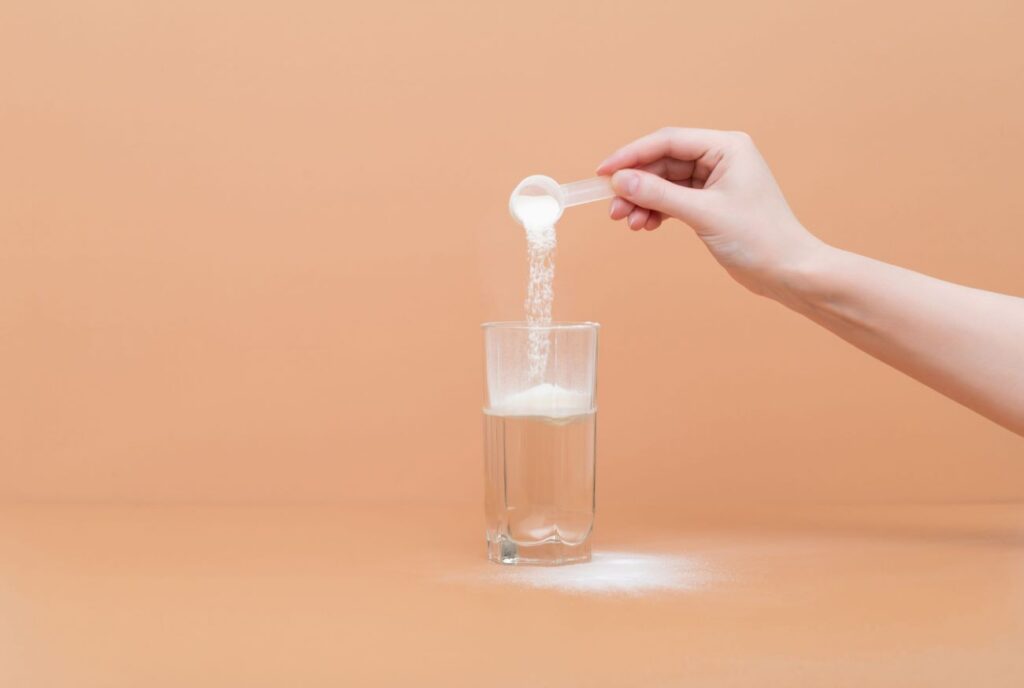Mulher despejando uma dose de creatina num copo com água