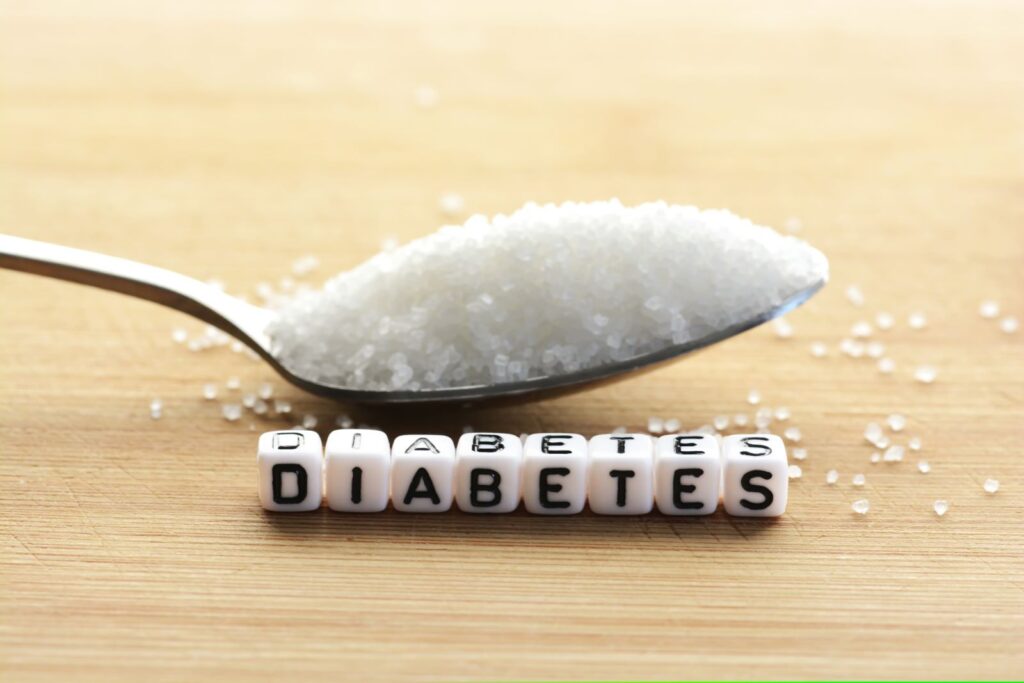 Colher cheia de açúcar branco atrás de letrinhas de plástico escrito "diabetes"