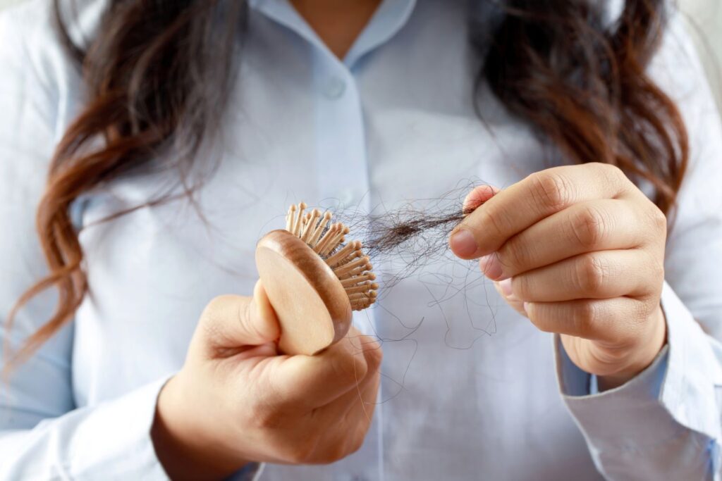 Mulher retirando um tufo de cabelos da sua escova
