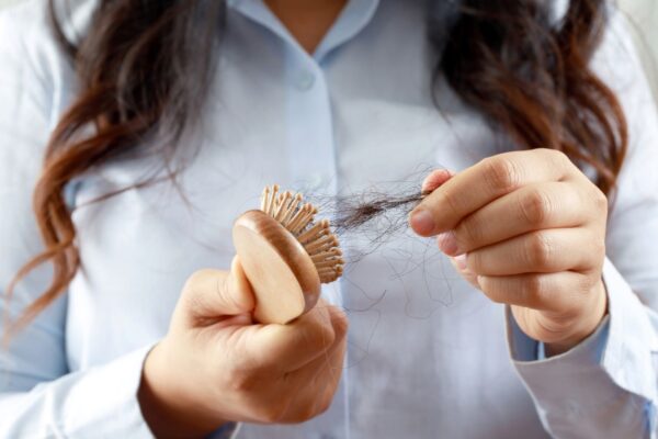 Mulher retirando um tufo de cabelos da sua escova