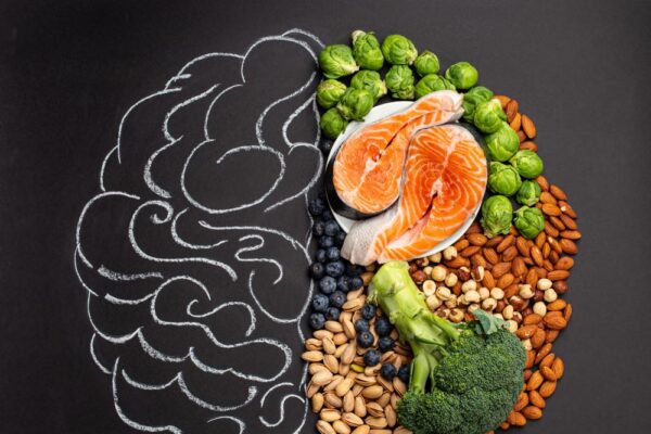 Imagem de um cérebro desenhado em giz e na metade do desenho há alimentos que fazem bem para a saúde cerebral
