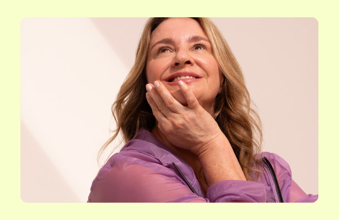 Mulher sorrindo com mão encostada no queixo.